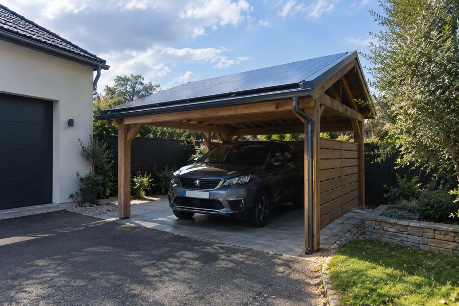 Carport en bois avec toiture photovoltaïque à côté d'une maison (photo d'illustration)